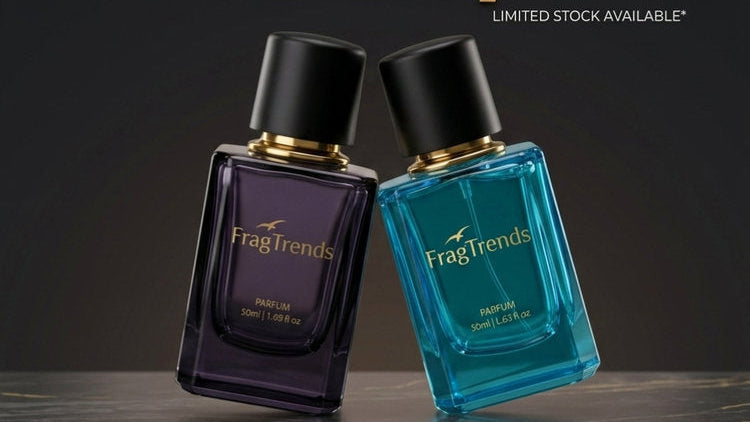 Promotional advertisement for Fragtrends perfumes showing two rectangular perfume bottles on a dark surface against a black background. One bottle is dark purple and the other is bright blue, both with black caps and gold lettering.